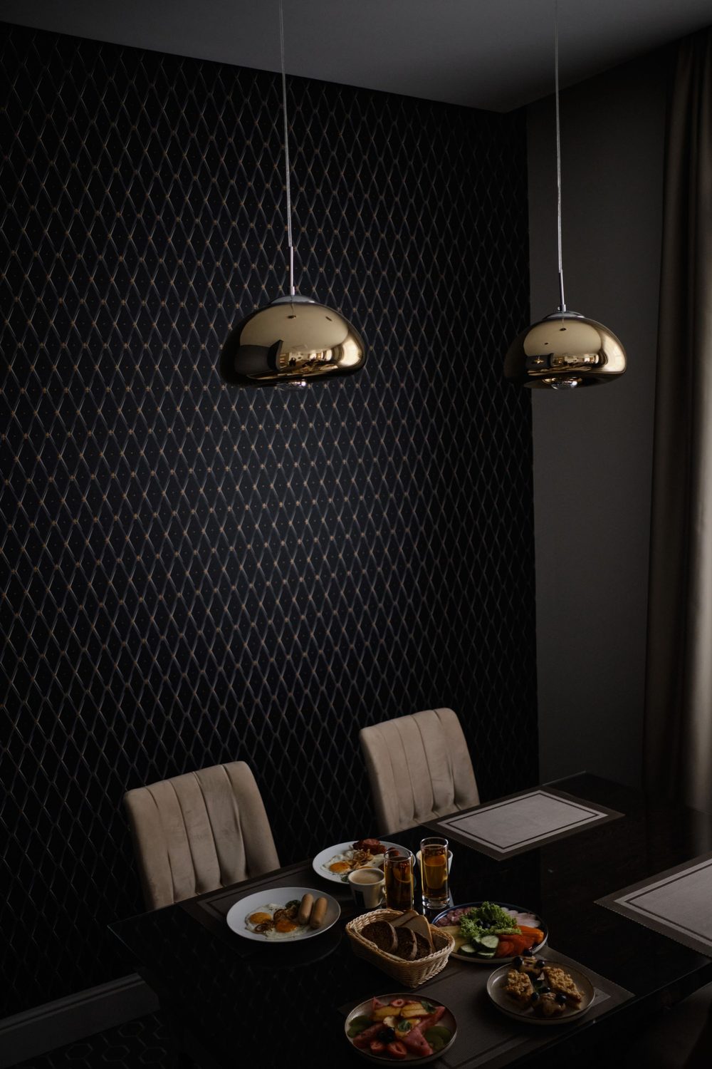 Cozy alcove with dark geometric wallpaper and brass pendant lights