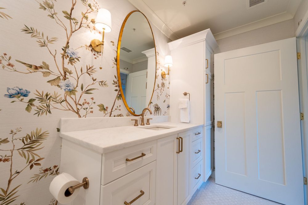 Powder room with chinoiserie floral wallpaper and a gold-framed mirror