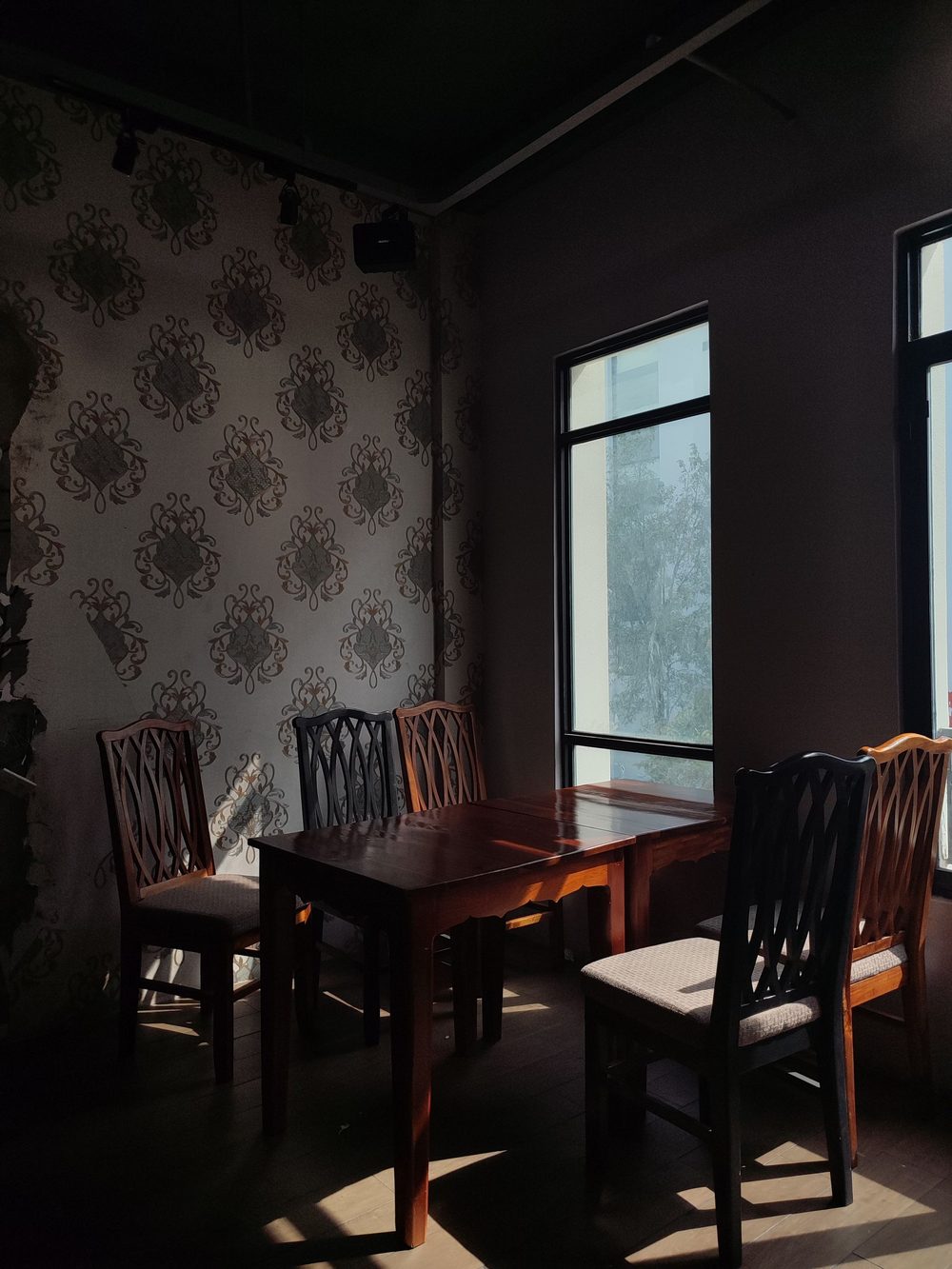 Formal dining room with an ornate dark damask wallpaper