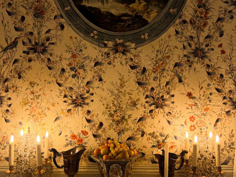 Dramatic dark floral wallpaper in a candlelit feature room