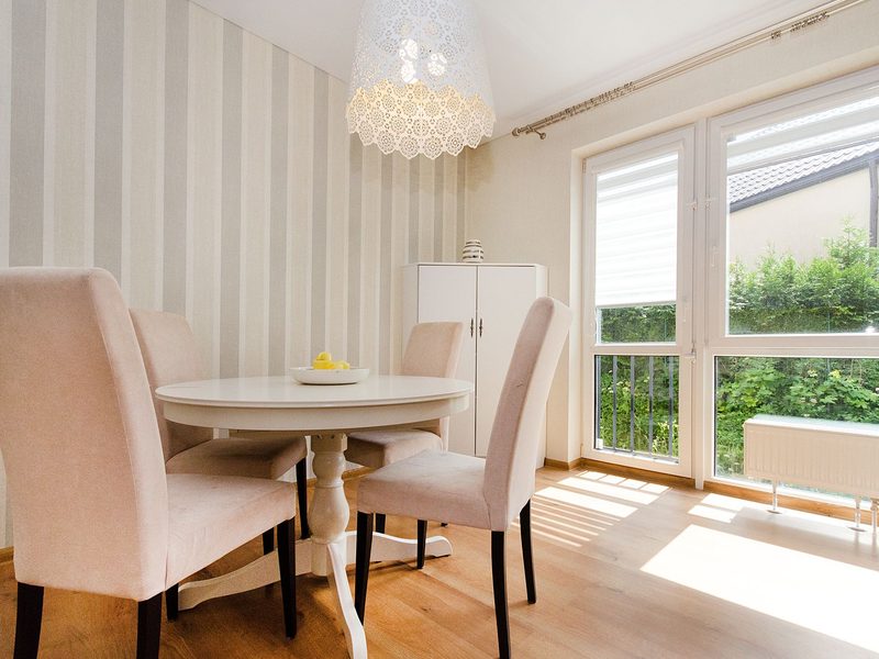 Bright dining room with a subtle damask wallpaper and pastel chairs
