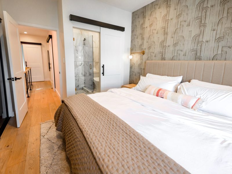 Bedroom with textured grasscloth wallpaper behind an upholstered headboard
